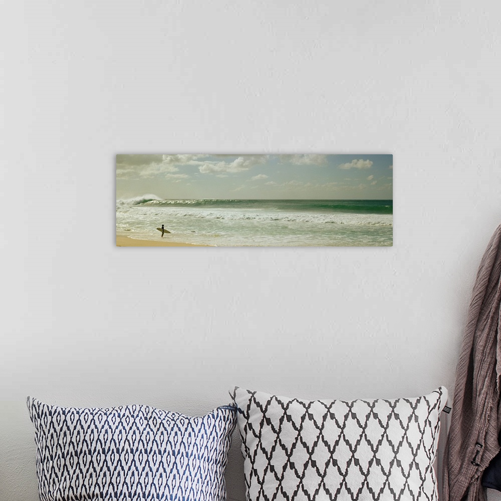 A bohemian room featuring Panoramic image of a surfer standing where the ocean meets the beach shore looking at a big wave ...