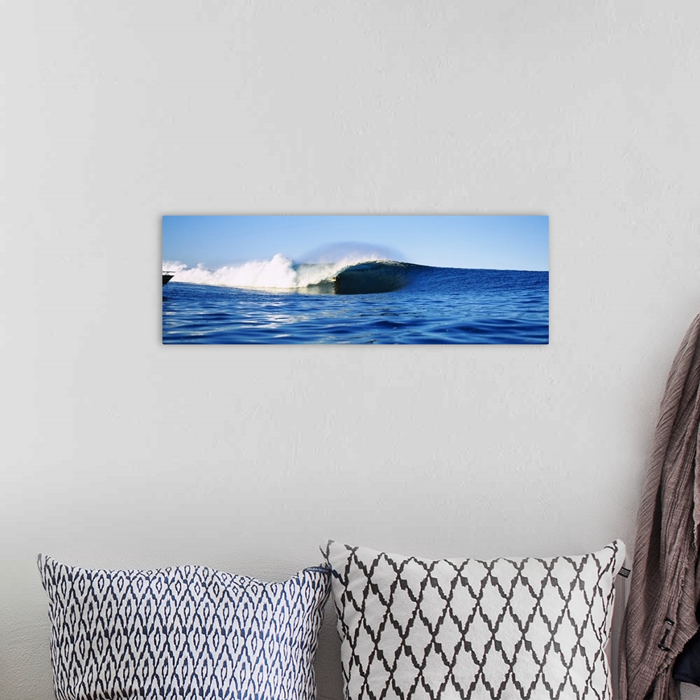 A bohemian room featuring Large, horizontal photograph of a distant surfer riding a large wave, in the blue waters of Tahit...