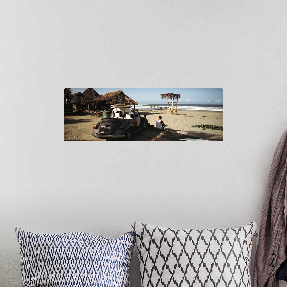 A bohemian room featuring A big panoramic photograph of surfers sitting in front of their car looking out at the ocean. Sma...