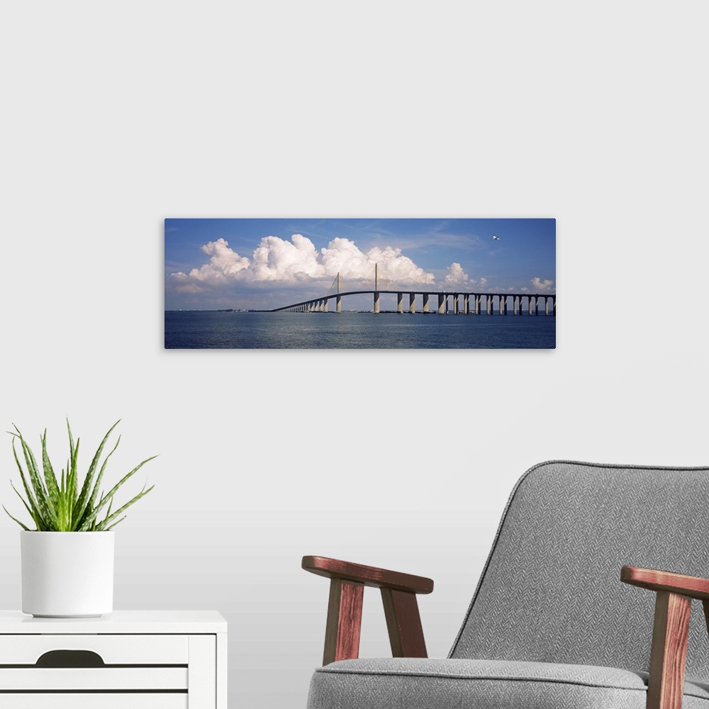 A modern room featuring Oversized, horizontal photograph of white fluffy clouds and a blue sky over the Sunshine Skyway B...