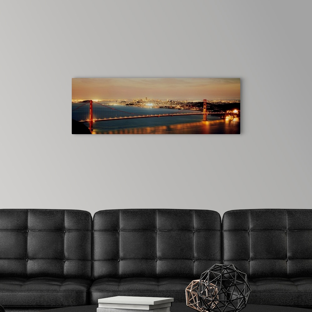 A modern room featuring Panoramic photograph shows the bright lights of the Golden Gate bridge as they reflect onto the w...