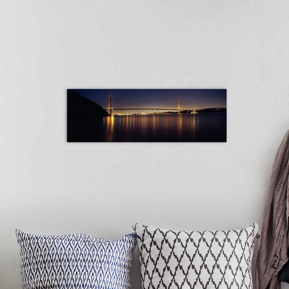 A bohemian room featuring Wide angle photograph of the Golden Gate Bridge in the distance, lit at night and reflecting over...