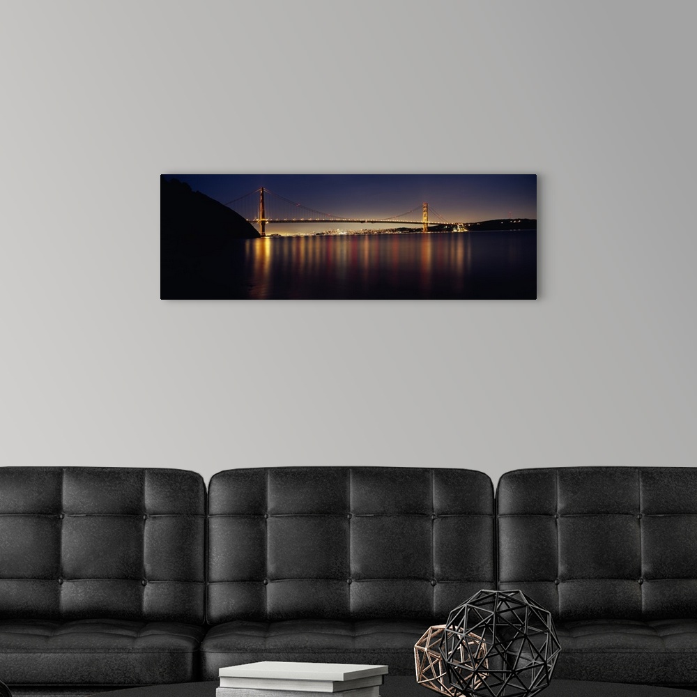 A modern room featuring Wide angle photograph of the Golden Gate Bridge in the distance, lit at night and reflecting over...