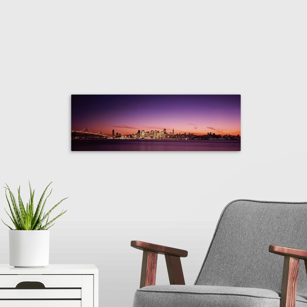 A modern room featuring Dusk panoramic photo looking across the San Francisco Bay at the buildings lit up in downtown San...