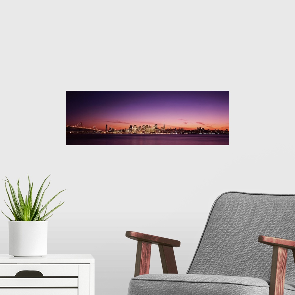 A modern room featuring Dusk panoramic photo looking across the San Francisco Bay at the buildings lit up in downtown San...