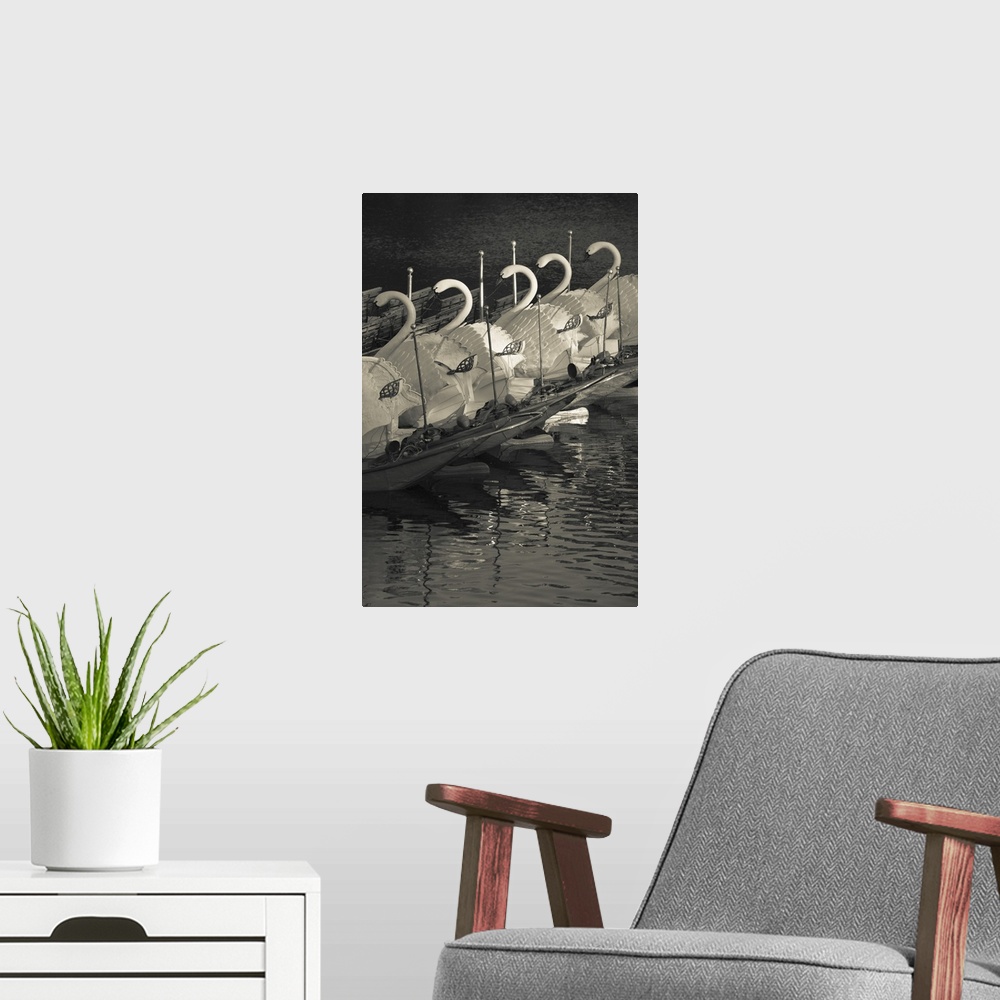 A modern room featuring Photograph of line of ships with huge swan structures docked.