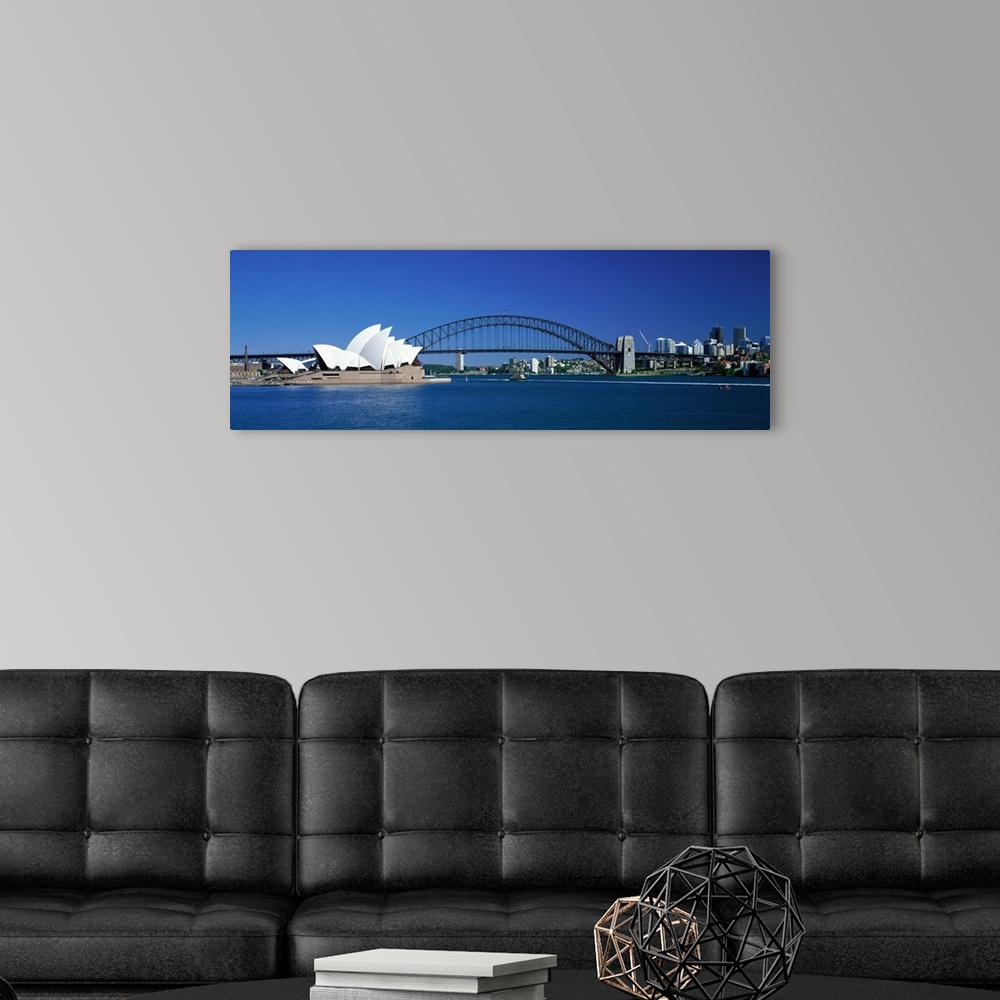 A modern room featuring This is a panoramic photograph of the harbor with the suspension bridge, opera house, and city sk...