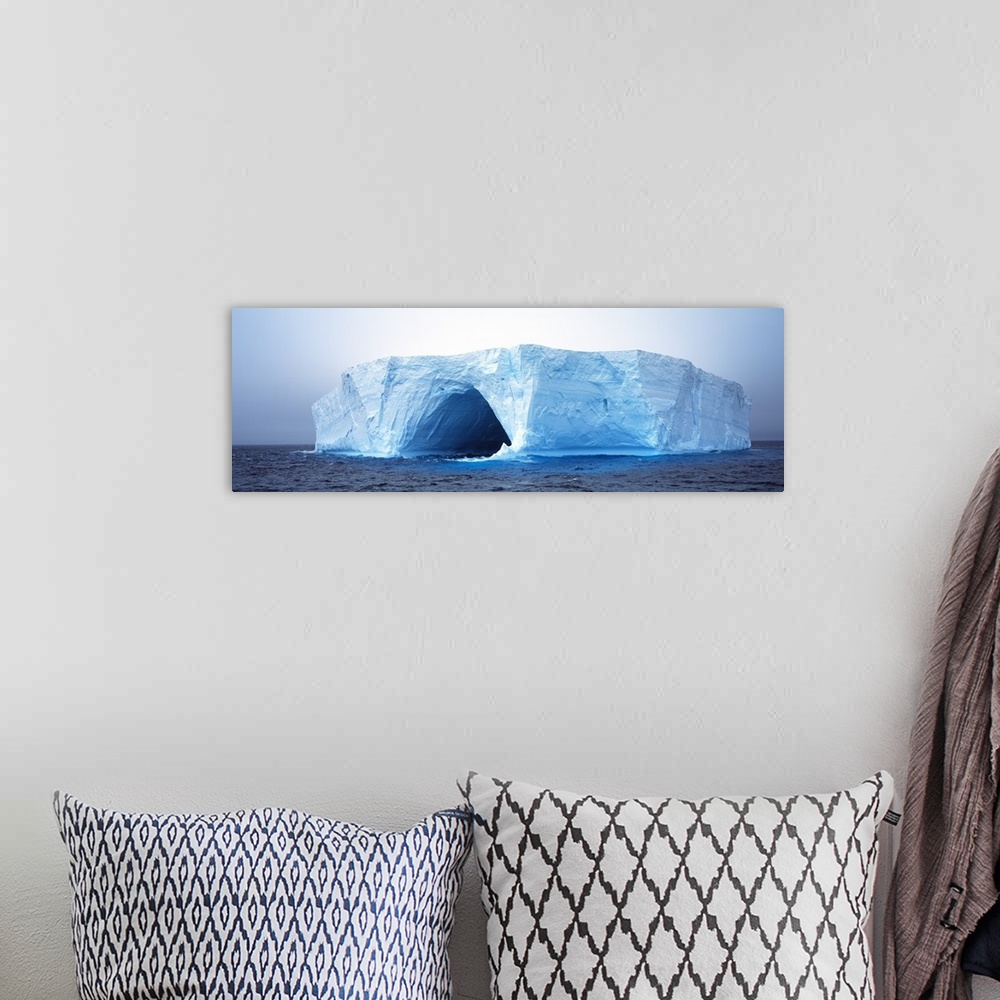 A bohemian room featuring This panoramic photograph is of an immense iceberg that has a tunnel going through the middle of it.