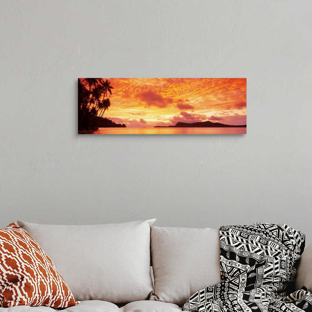 A bohemian room featuring Panoramic photograph includes a vivid sunset over a beach filled with palm trees.  In the backgro...
