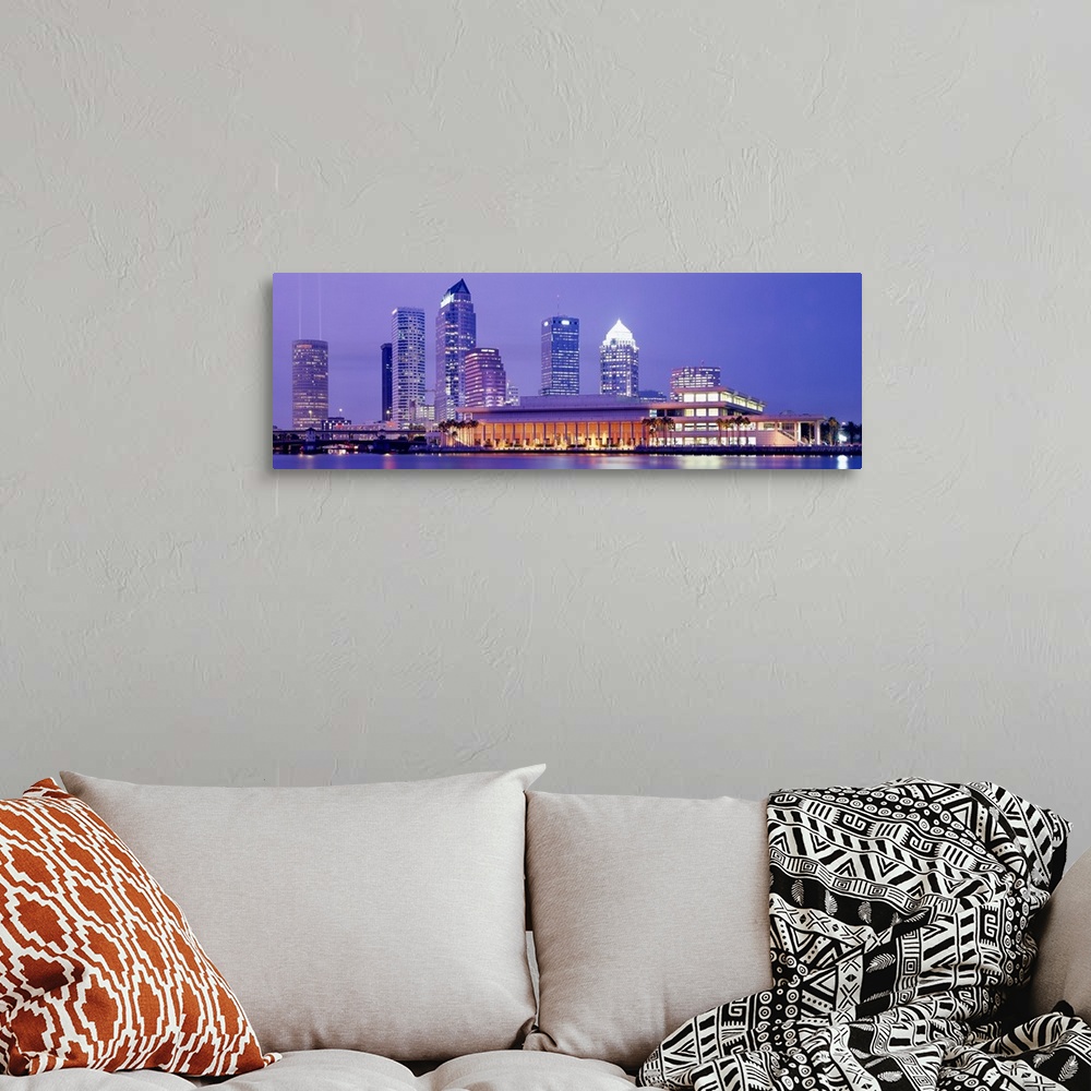 A bohemian room featuring The Tampa skyline is photographed in panoramic view during the night with the buildings all illum...