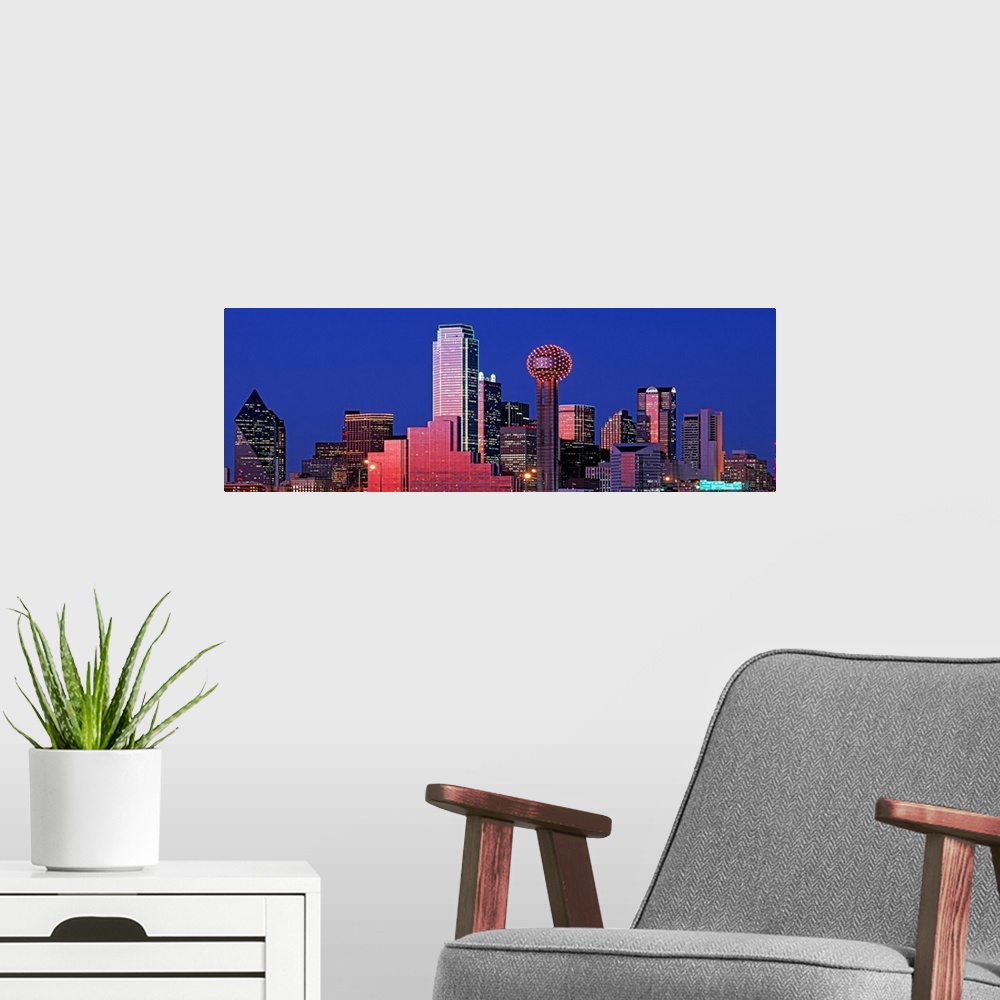 A modern room featuring This wall art is a panoramic photograph of the city skyline glowing and glimmering in the night sky.