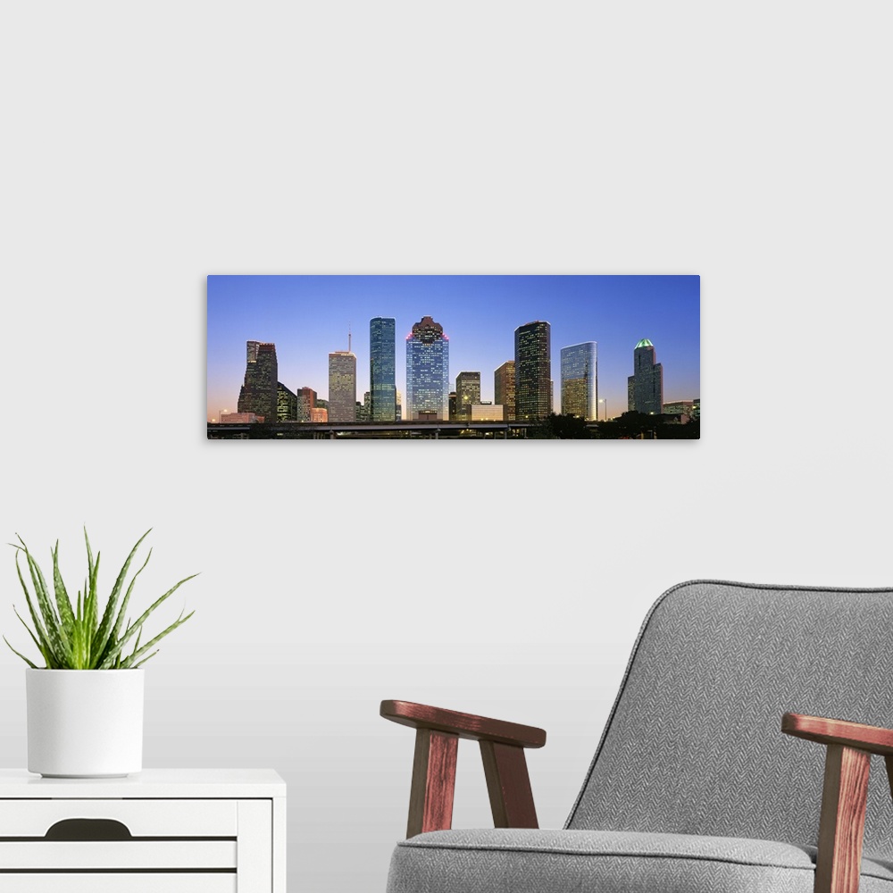 A modern room featuring Panoramic photo of a cityscape at dusk with the lights on in some of the buildings.