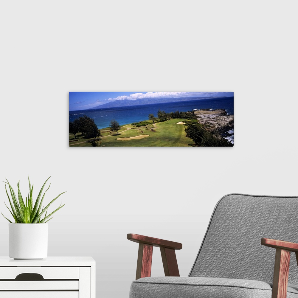 A modern room featuring This panoramic photograph is a golf landscape overlooking the ocean from a tropical island.