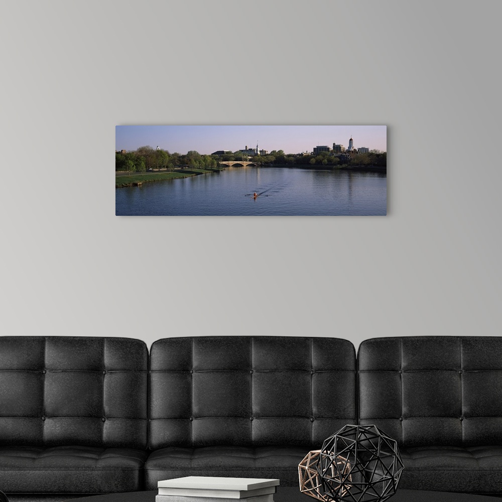 A modern room featuring Panoramic photograph of rower in lake lined by trees with bridge in the distance under a clear sky.
