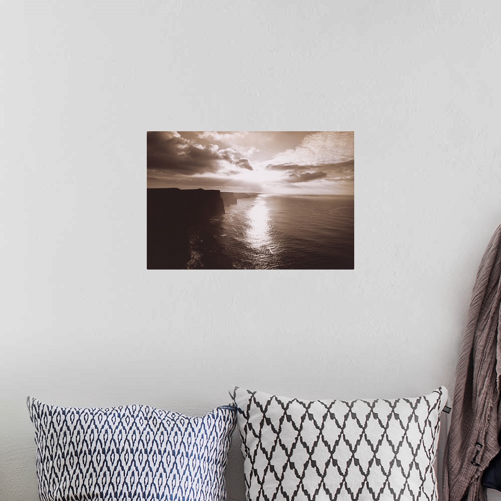 A bohemian room featuring This big artwork piece is of a sepia toned sunset reflecting in the ocean water below with immens...