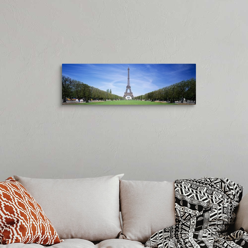 A bohemian room featuring Tree lined grassy field in Paris with the Eiffel Tower protruding in to the clear blue sky.