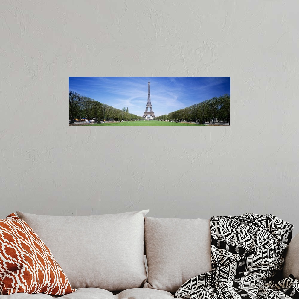 A bohemian room featuring Tree lined grassy field in Paris with the Eiffel Tower protruding in to the clear blue sky.