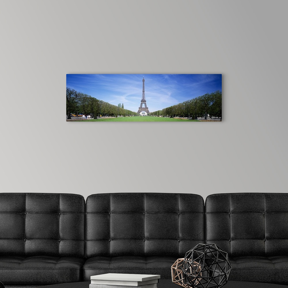 A modern room featuring Tree lined grassy field in Paris with the Eiffel Tower protruding in to the clear blue sky.