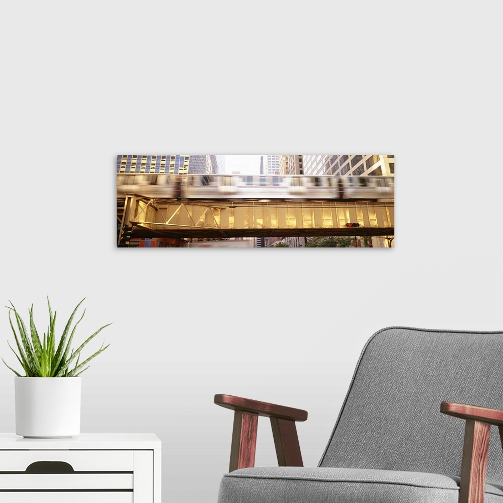 A modern room featuring Pamoramic style photo of a commuter train in Chicago flying by on an elevated bridge in downtown.