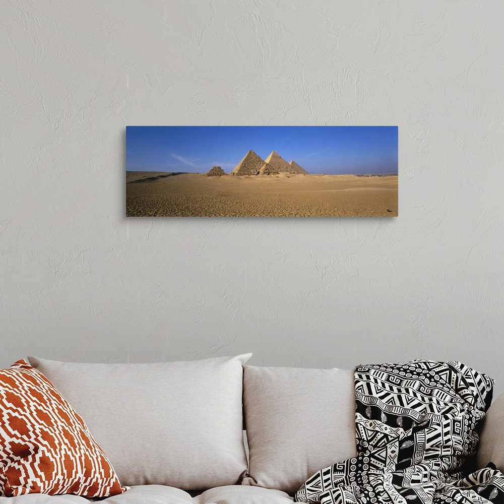 A bohemian room featuring The pyramids in Egypt are photographed in wide angle view from a distance with a clear blue sky b...