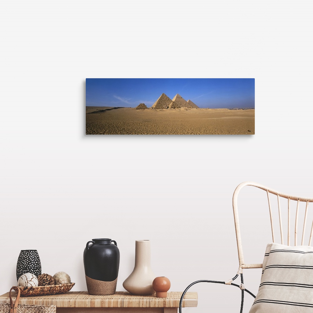 A farmhouse room featuring The pyramids in Egypt are photographed in wide angle view from a distance with a clear blue sky b...