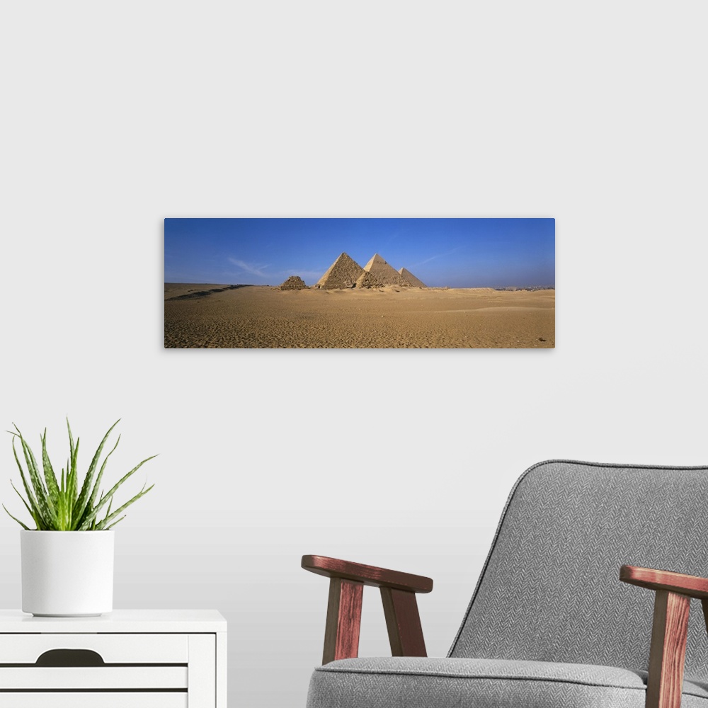 A modern room featuring The pyramids in Egypt are photographed in wide angle view from a distance with a clear blue sky b...