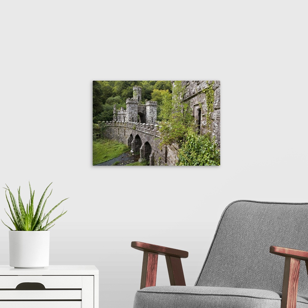 A modern room featuring A side angle view of a large stone bridge and towers that are surrounded by greenery in Ireland.