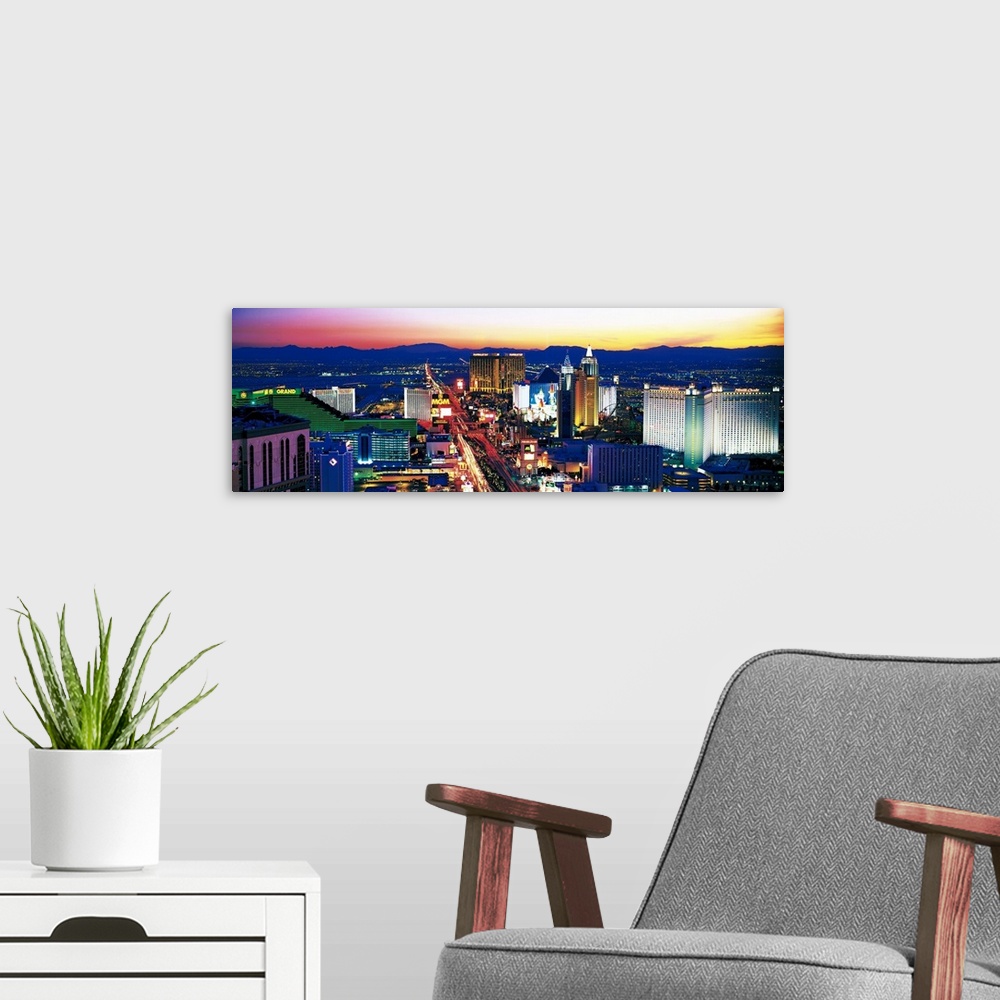 A modern room featuring Panoramic photograph of city at sunset with mountains in the distance.  The buildings are brightl...