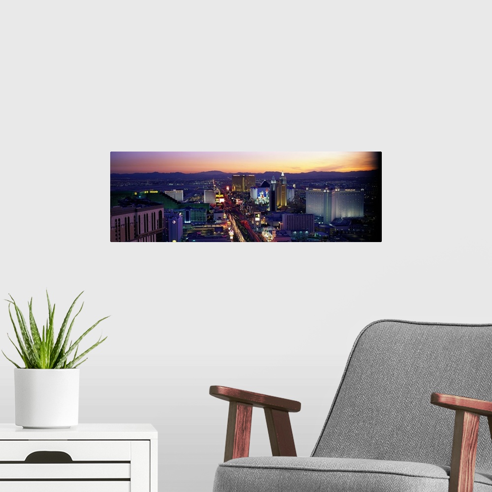 A modern room featuring Panoramic photograph of ""Sin City"" skyline at sunset with buildings lit up and mountains in the...