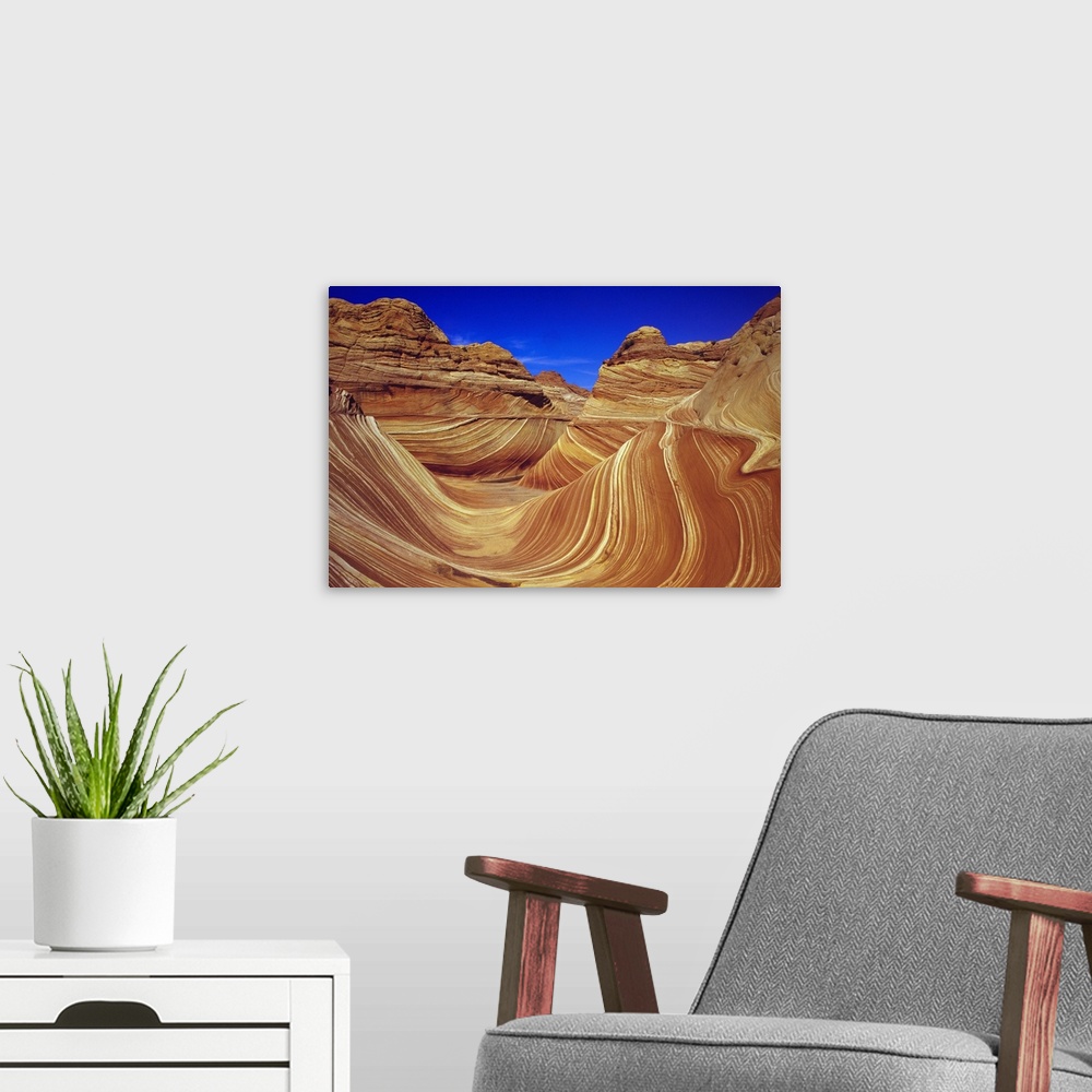A modern room featuring Giant, horizontal photograph of the sandstone formation The Wave, against a deep blue sky in the ...