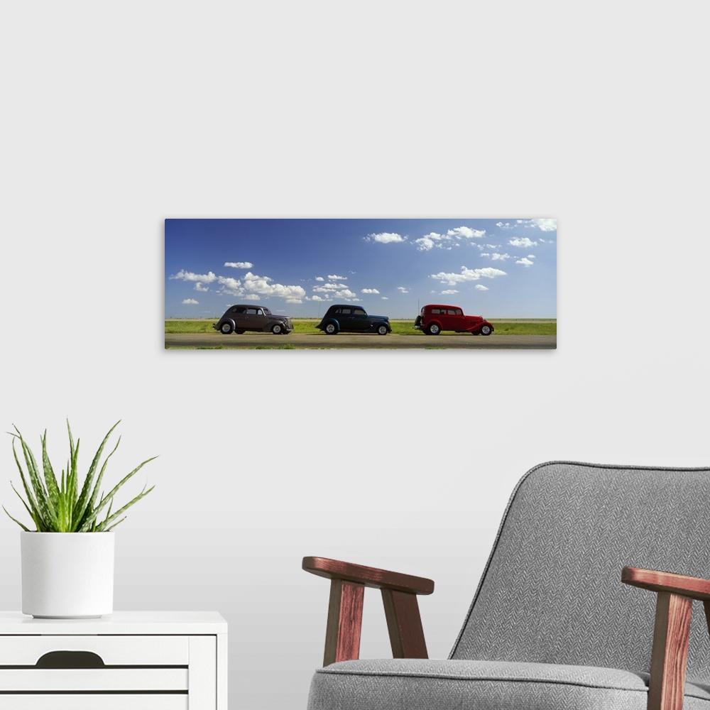 A modern room featuring Panoramic photograph of three vintage cars driving down the street under cloudy skies.