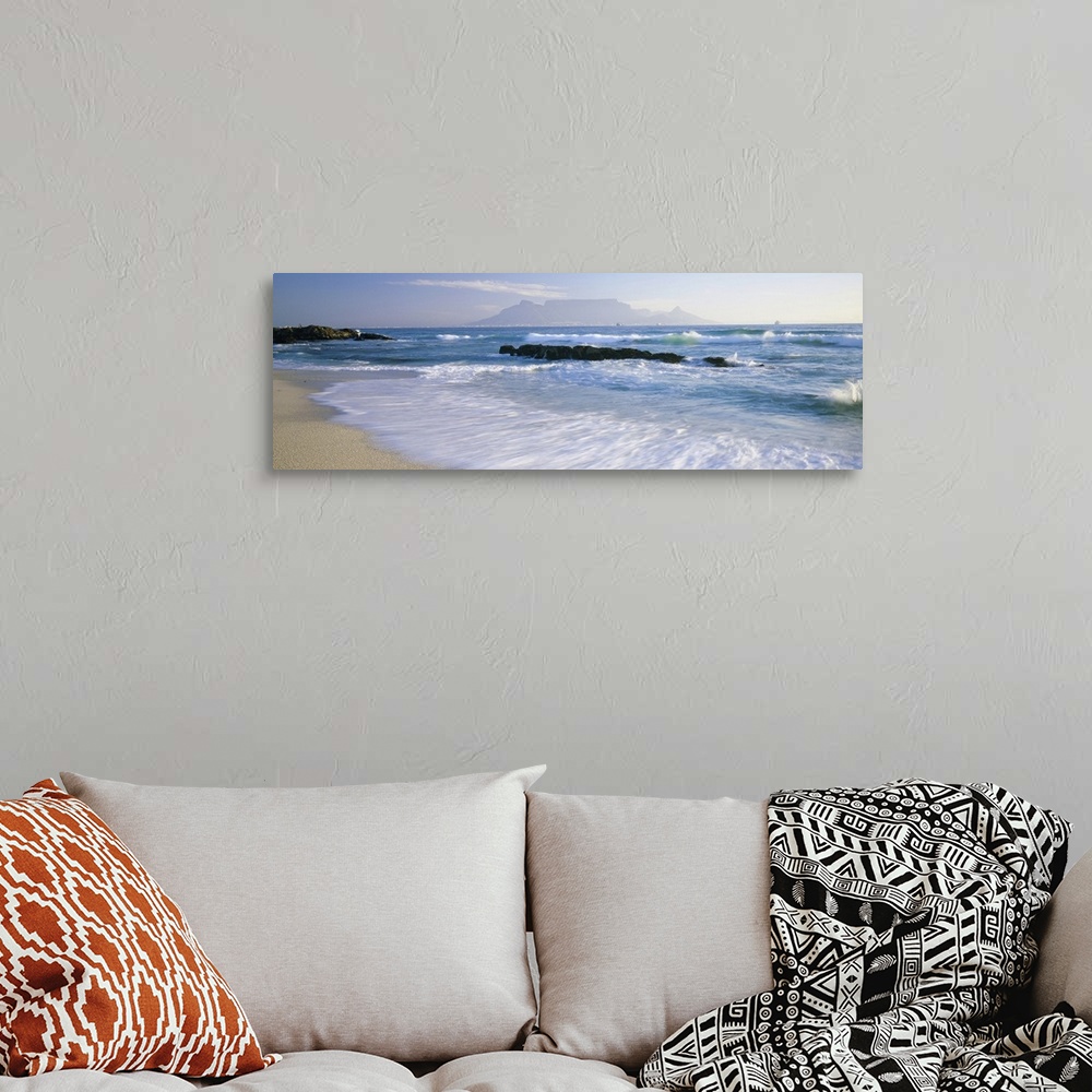 A bohemian room featuring Panoramic photograph taken of the ocean with waves crashing and rushing onto the shore line. Rock...