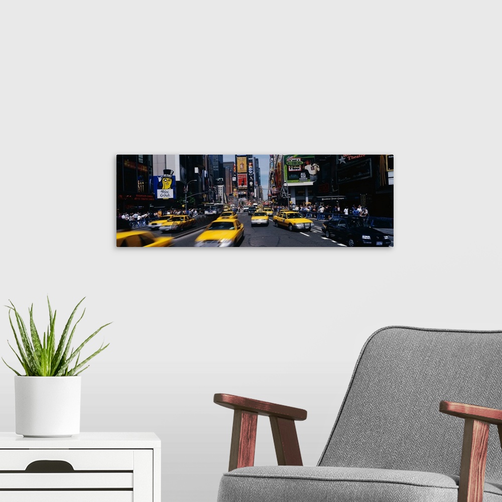 A modern room featuring Wide angle photograph of many taxi cabs rushing through the streets, surrounded by the large adve...