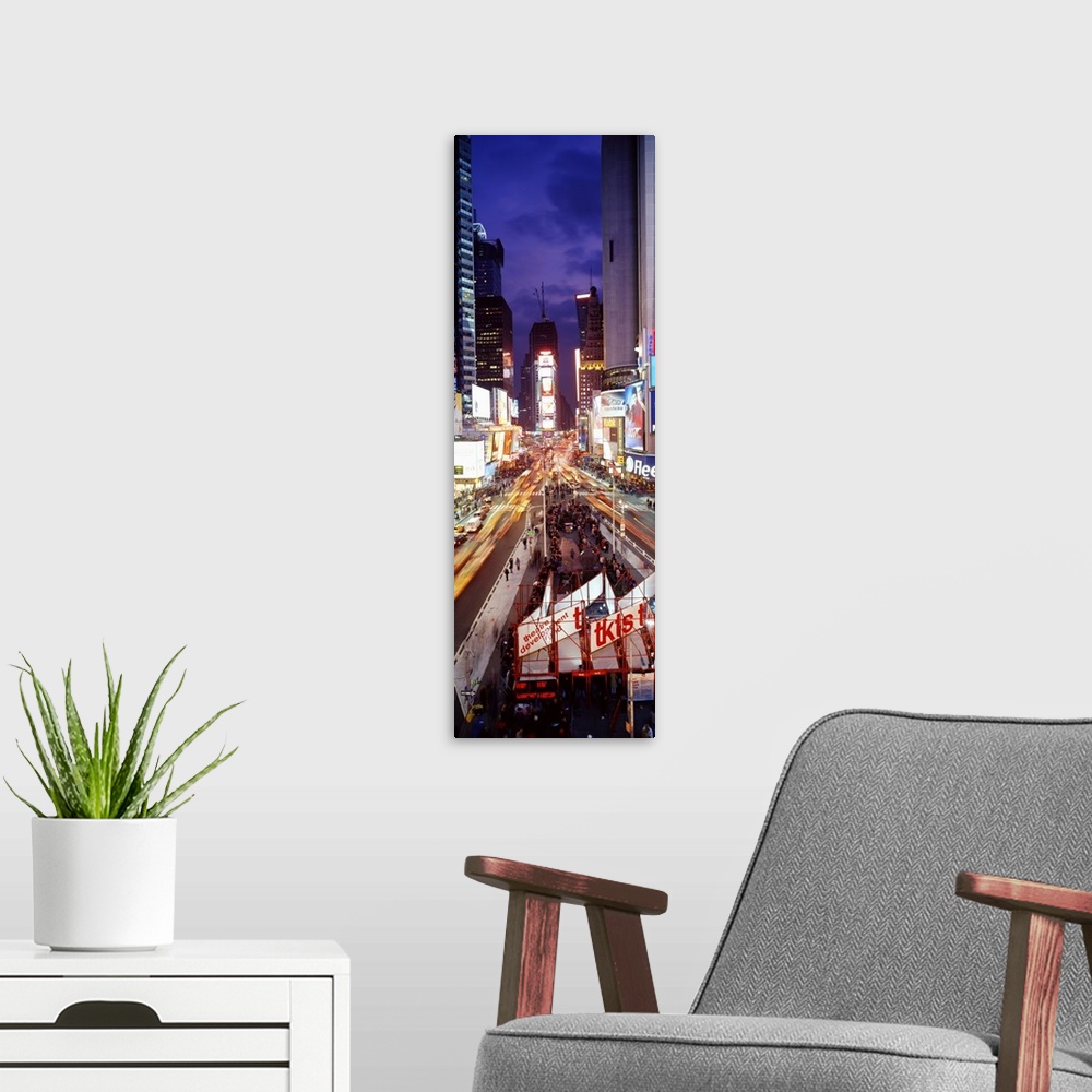 A modern room featuring Vertical panoramic of a busy Times Square at night with traffic lined streets and tourists in lin...