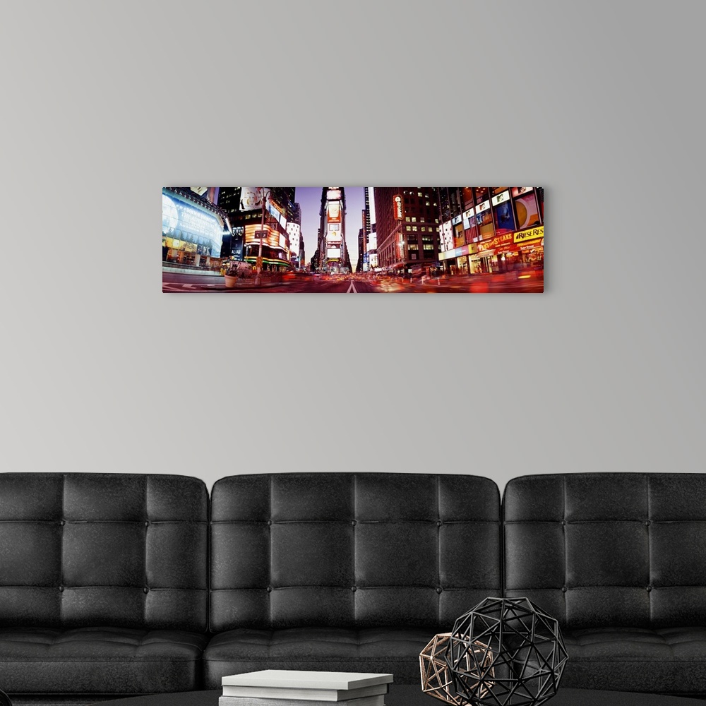 A modern room featuring Part of Times Square is photographed in panoramic view while it's illuminated under the dusk sky.
