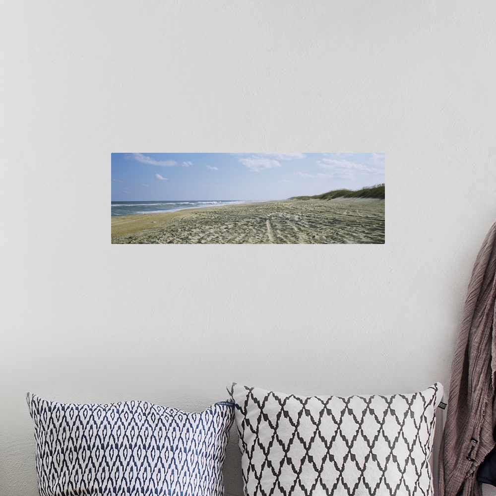 A bohemian room featuring A panoramic photograph of a sandy beach indented with footsteps and tracks down to the ocean water.