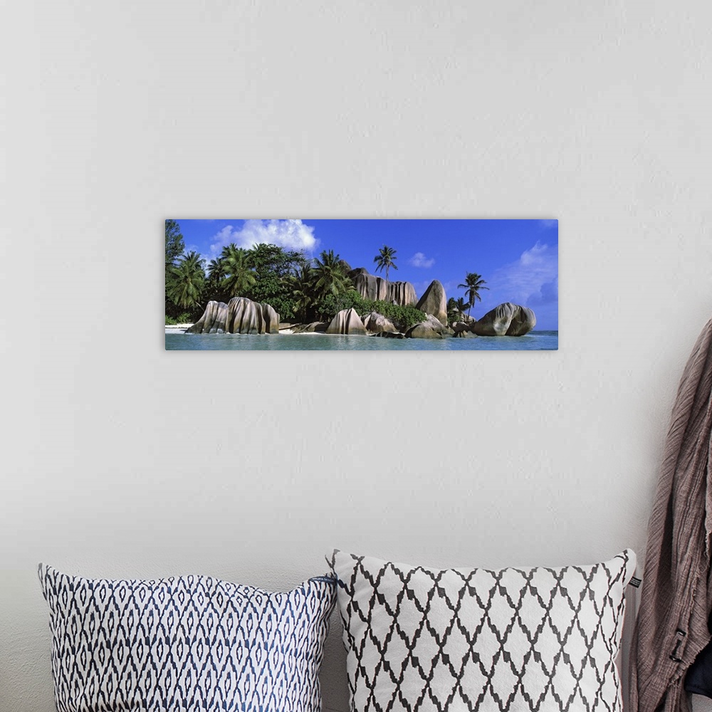 A bohemian room featuring Panoramic canvas photo of big smooth rocks on an ocean shore with a forest of palm behind them.