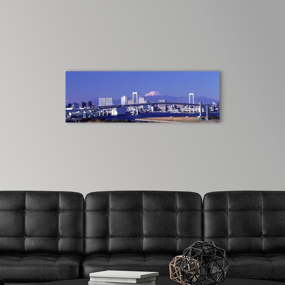 A modern room featuring Large panoramic piece of the Tokyo skyline with a bridge and buildings in full view and a mountai...