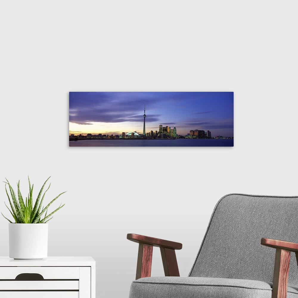 A modern room featuring This panoramic view is the city skyline at twilight taken from over the water.