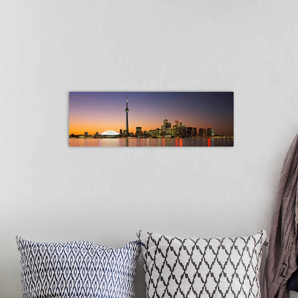 A bohemian room featuring Panoramic image of a cityscape at dusk with lights reflecting off of the water.