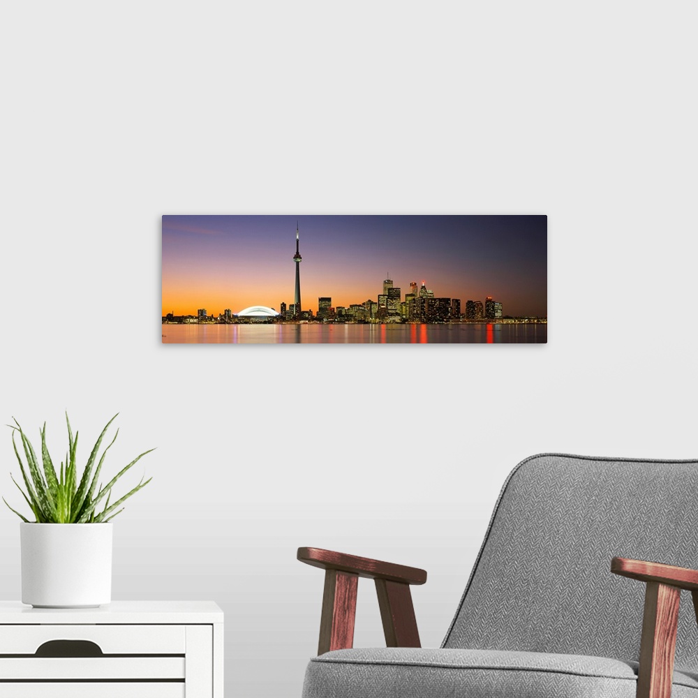 A modern room featuring Panoramic image of a cityscape at dusk with lights reflecting off of the water.