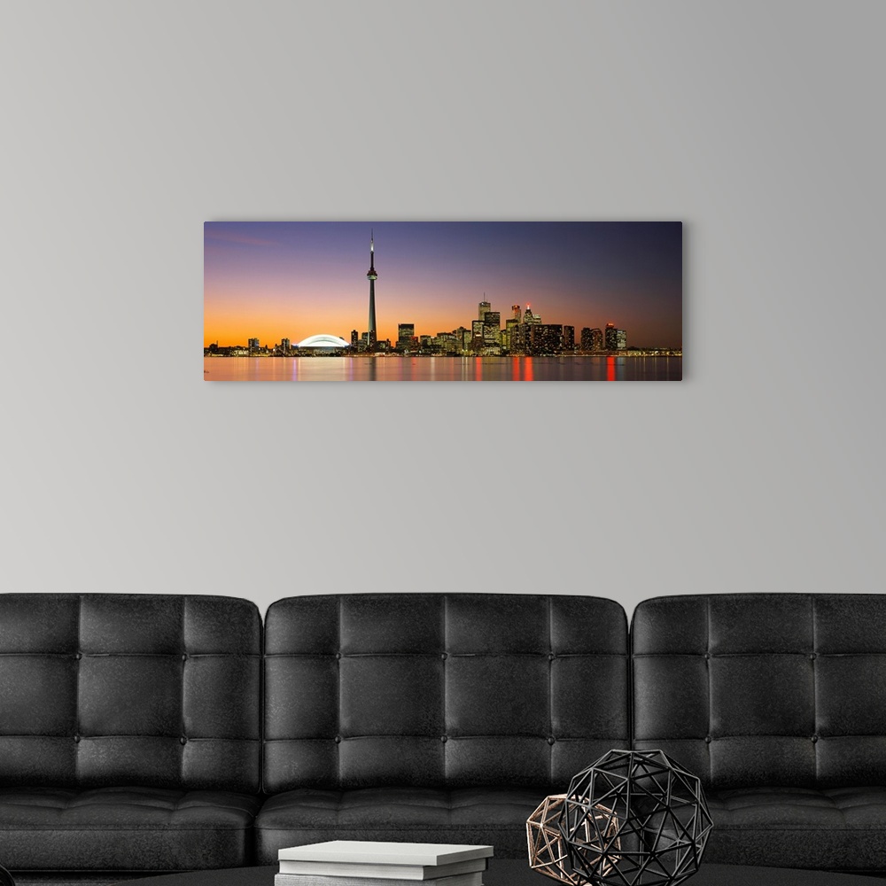 A modern room featuring Panoramic image of a cityscape at dusk with lights reflecting off of the water.