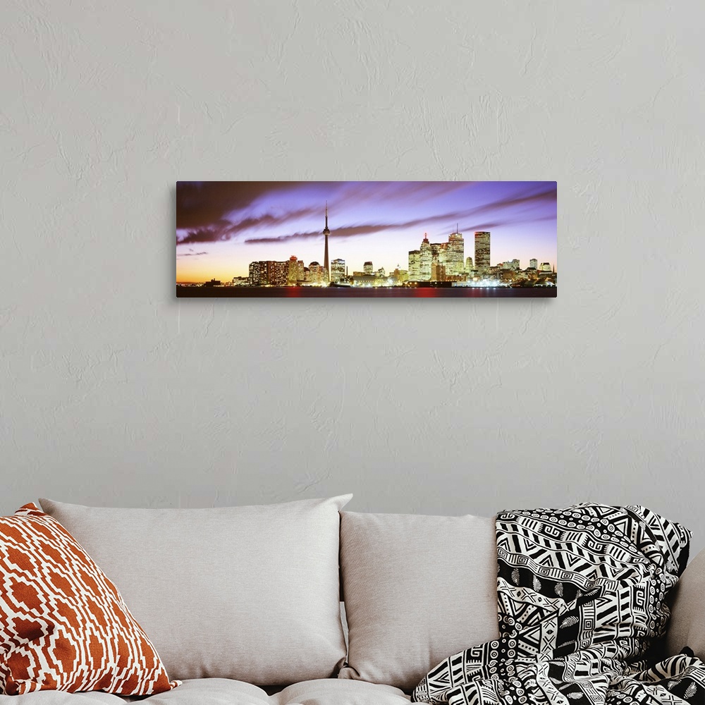 A bohemian room featuring Wide angle photograph of the Toronto skyline, including CN Tower, lit up at dusk, beneath whippin...