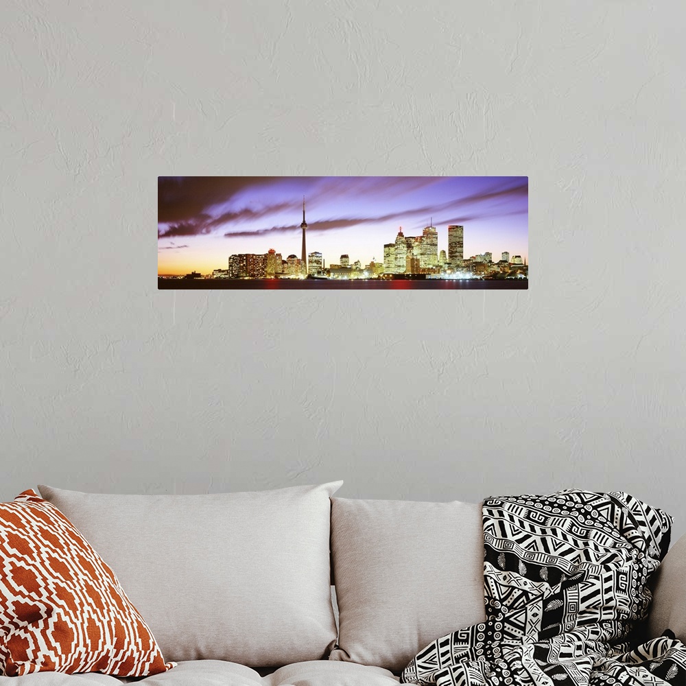 A bohemian room featuring Wide angle photograph of the Toronto skyline, including CN Tower, lit up at dusk, beneath whippin...