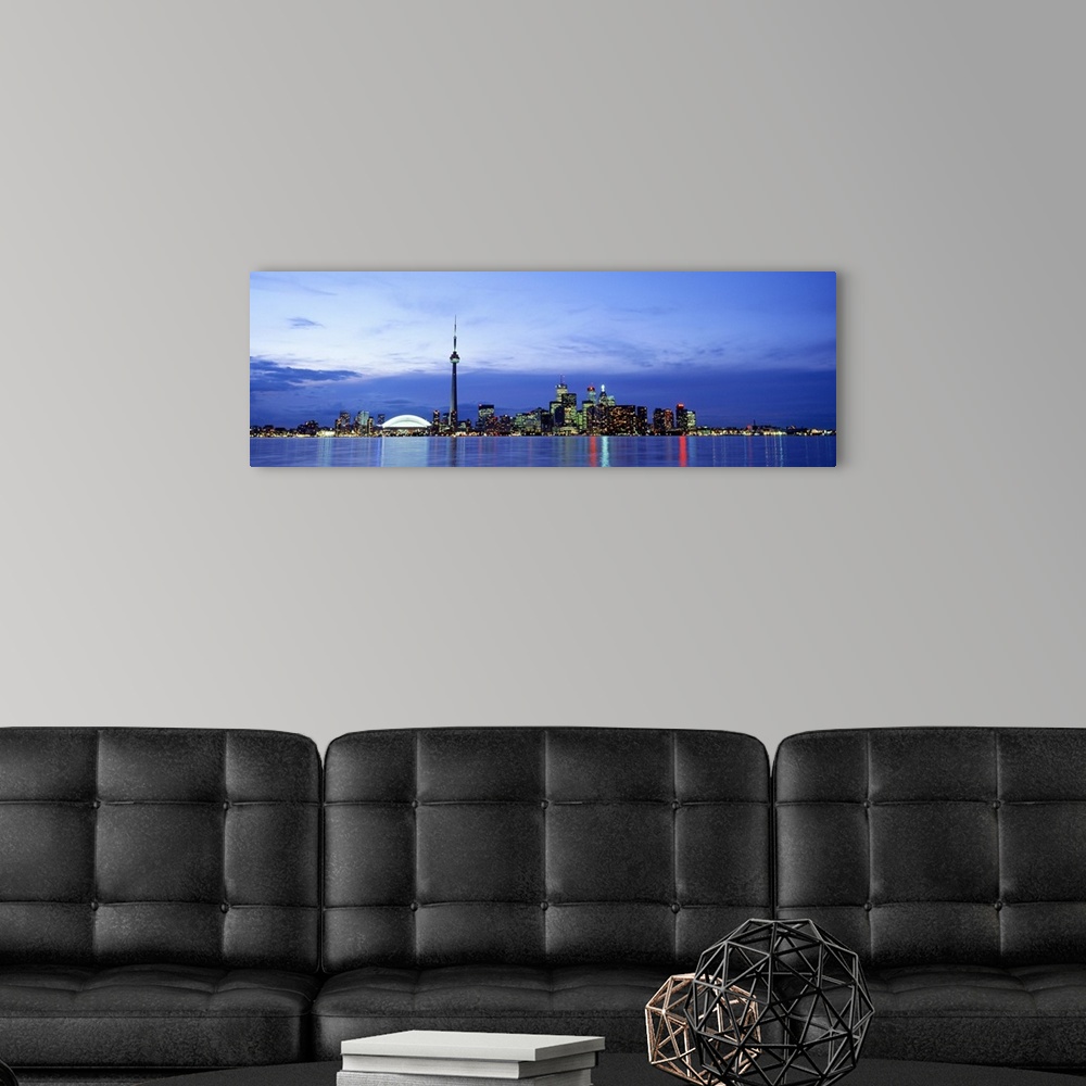 A modern room featuring A wide angle photograph taken of an illuminated skyline in Canada at dusk. The lights reflect in ...