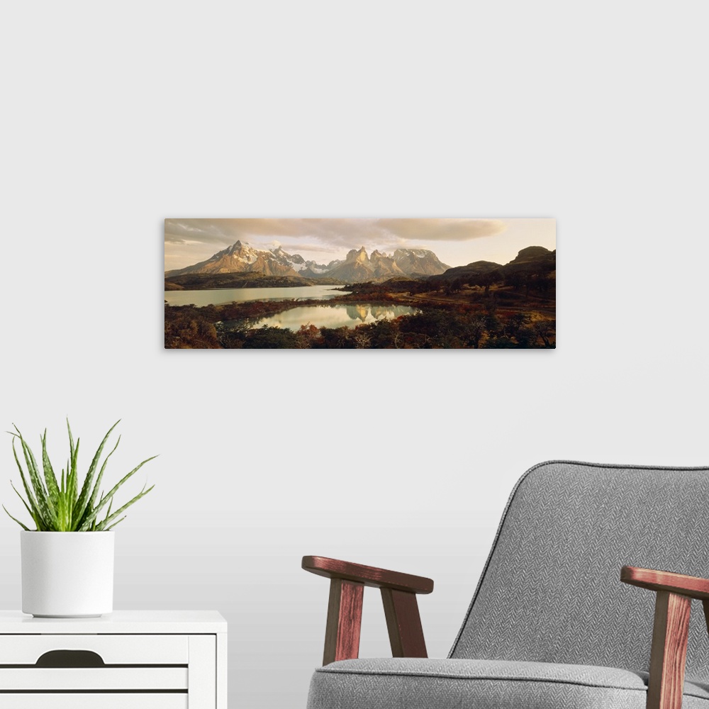A modern room featuring Big, landscape, wide angle photograph of snow covered mountains behind waters surrounded by fores...
