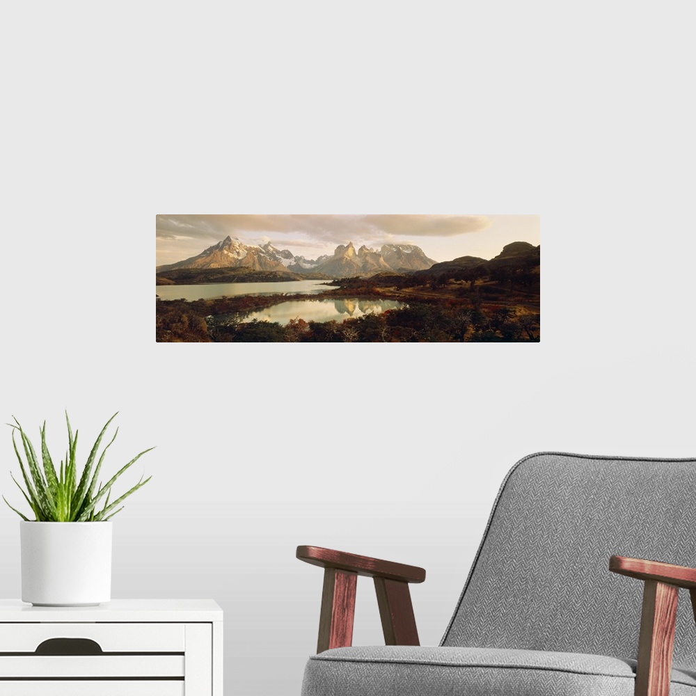 A modern room featuring Big, landscape, wide angle photograph of snow covered mountains behind waters surrounded by fores...