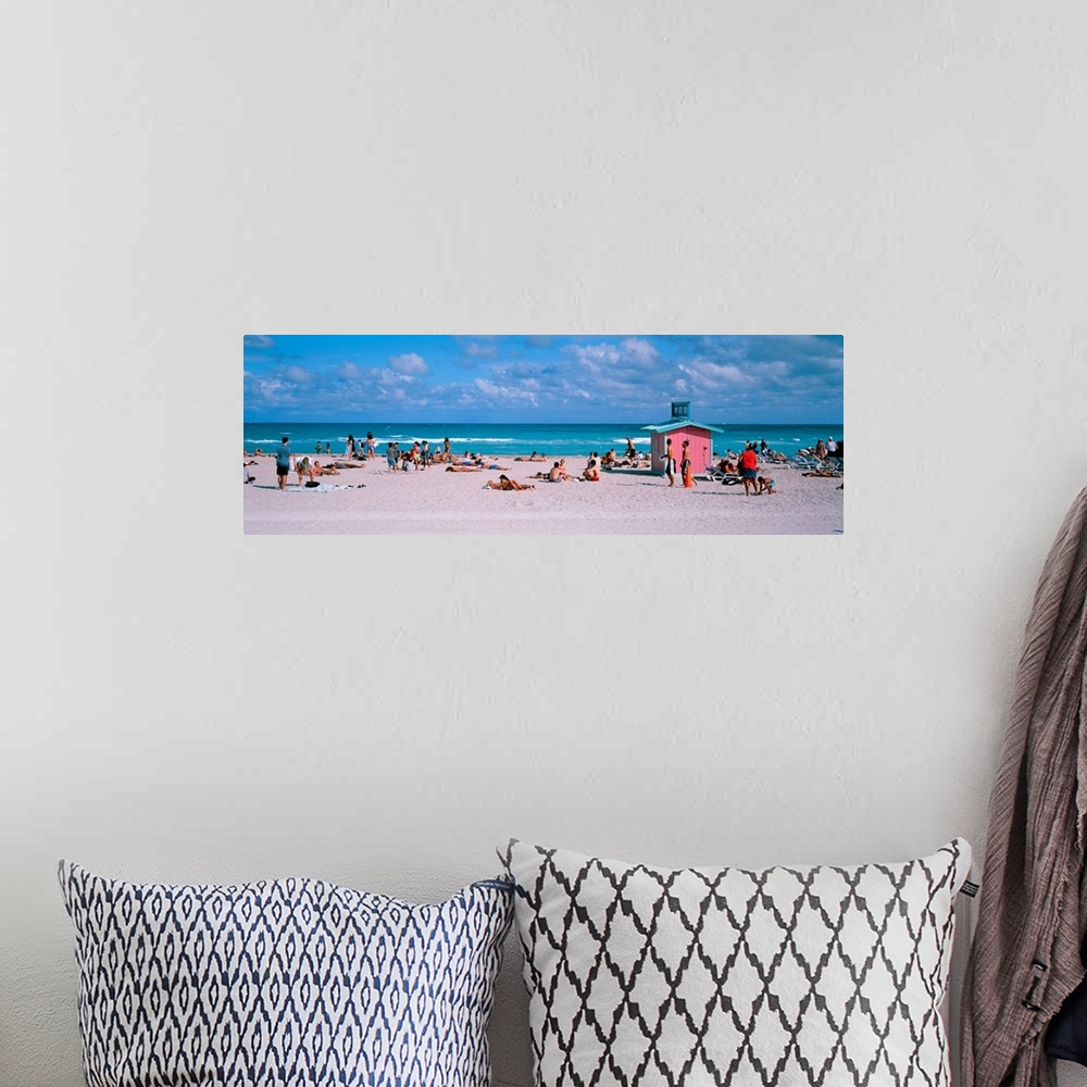 A bohemian room featuring Long horizontal print of people out and about on the beach with crashing waves behind them.