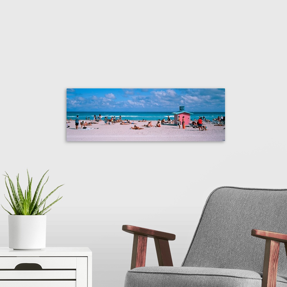 A modern room featuring Long horizontal print of people out and about on the beach with crashing waves behind them.