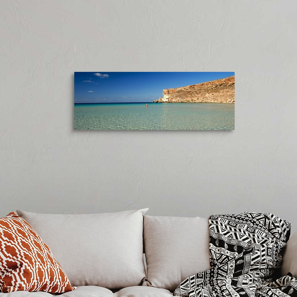 A bohemian room featuring Tourist walking in the sea, Spiaggia Dei Conigli, Italy